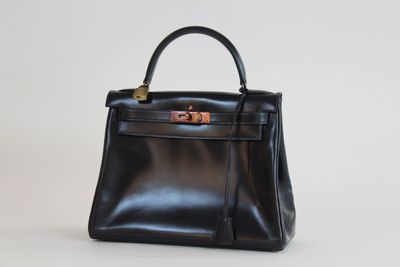 un sac à main en cuir noir posé sur une surface blanche