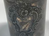 a silver cup with a design on it on a white surface