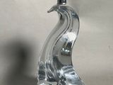 a clear glass sculpture of a bird on a table