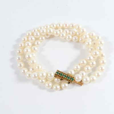 an image of a white pearl bracelet with a gold clasp and emerald clasp