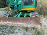 a green and yellow bulldozer that is parked in the dirt