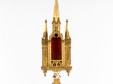 a gold - plated clock with a red glass in front of it