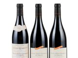 three bottles of wine are lined up on a white surface