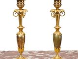 pair of antique brass candlesticks on marble table against white background