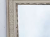 a mirror hanging on a wall with a sky in the background