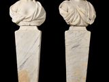two white marble busturines of women on pedestals against a black background
