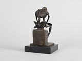 statue of a skeleton sitting on top of a block with a bird perched on it ' s head
