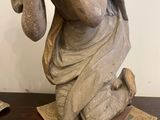 statue of a woman holding a basket of flowers on top of a wooden table
