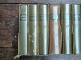 four old books are lined up on a wooden table