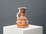 a brown and white vase sitting on top of a white pedestal