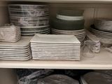 many plates and bowls on the shelves in the kitchen