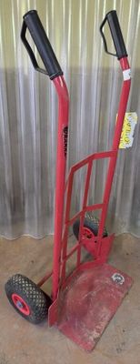 a red hand truck with two black wheels on the floor