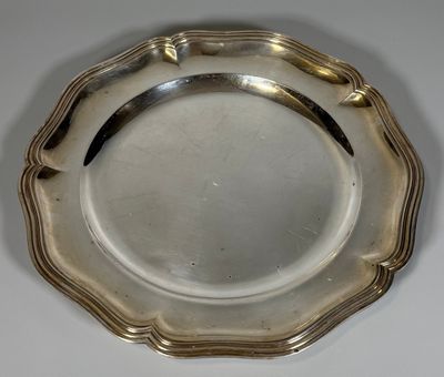 un plat ancien en argent posé sur une table blanche, muni d'une poignée noire
