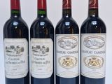 quatre bouteilles de vin sont alignées sur une surface blanche