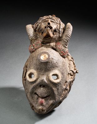 une sculpture en argile représentant une tête surmontée d'un singe