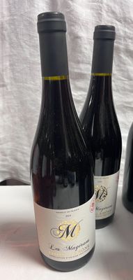 Trois bouteilles de vin sont posées sur une table recouverte d'une nappe blanche.