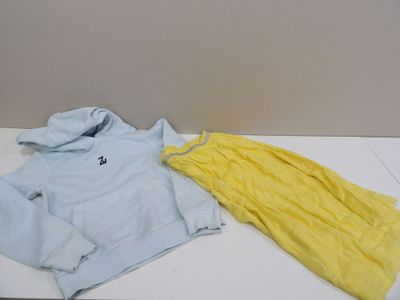 un sweat à capuche bleu et un pantalon jaune posés sur une table blanche