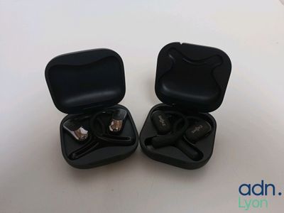 two black earphones in a black case on a white surface