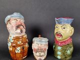 three ceramic figurines of men with hats and beards on them
