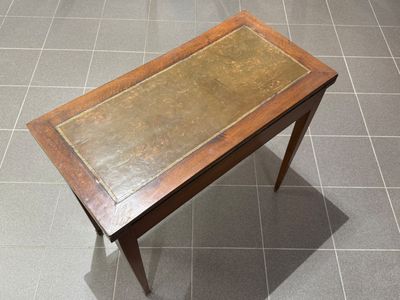 a small table with a leather top on a tiled floor