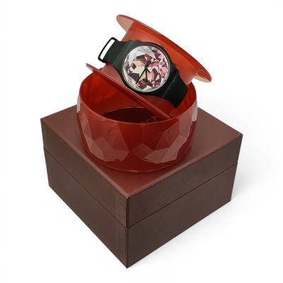 une montre posée sur une boîte, sur une surface blanche
