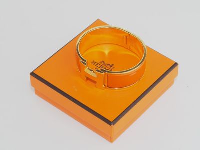 une boîte orange surmontée d'un anneau, posée sur une surface blanche