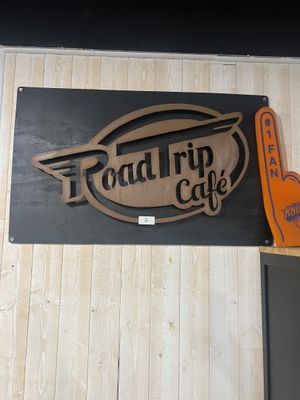 a sign that says road trip cafe on the side of the building