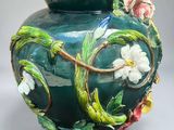 a green vase with flowers and vines painted on it