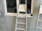 trois échelles adossées au mur près d'une fenêtre