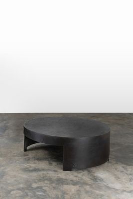 une table basse noire posée sur un sol en béton