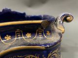 a close up of a blue and gold vase on a table