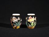 deux vases décorés de poissons et de plantes, posés sur une surface noire
