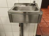 un lavabo en acier inoxydable dans des toilettes publiques aux murs carrelés
