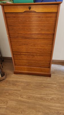 une armoire en bois sur laquelle est posé un sac bleu et vert