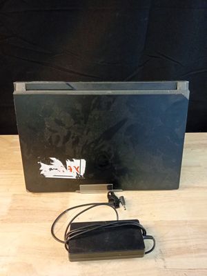 un ordinateur portable posé sur une table en bois, avec son chargeur