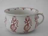 a white cup with red designs on it on a white surface