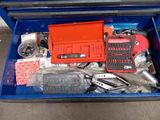 une boîte bleue posée par terre, contenant des outils