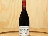 a bottle of wine sitting on top of a barrel