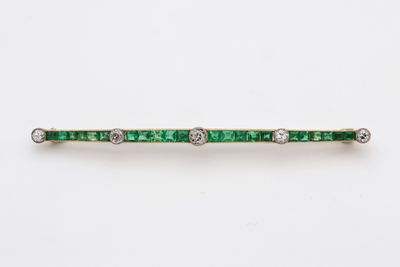 Gros plan sur une broche en forme de barre sertie d'émeraudes et de diamants