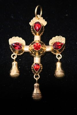 un gros plan d'une croix ornée de clochettes sur un fond noir
