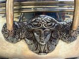 a silver vase with a face on the handle