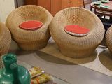three wicker chairs with red cushions sit in a living room