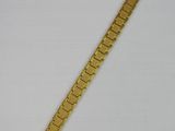 a close up of a gold bracelet on a white surface