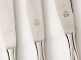 three silverware knives are lined up on a white surface