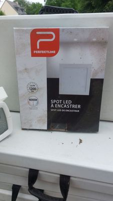 une horloge blanche posée sur le rebord d'une fenêtre, à côté d'une boîte