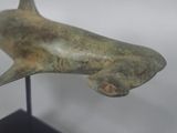 statue of a shark on a black stand on a white background