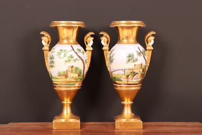deux vases en or posés sur une table en bois, sur fond noir
