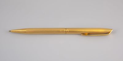a gold pen sitting on top of a white surface