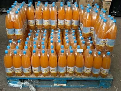 bottles of orange juice are stacked on a pallet in a warehouse