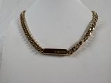 the necklace is gold and has a name plate on it